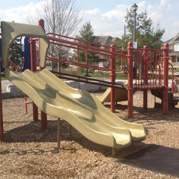 A playground slide with a Fibertop wear mat at the bottom
