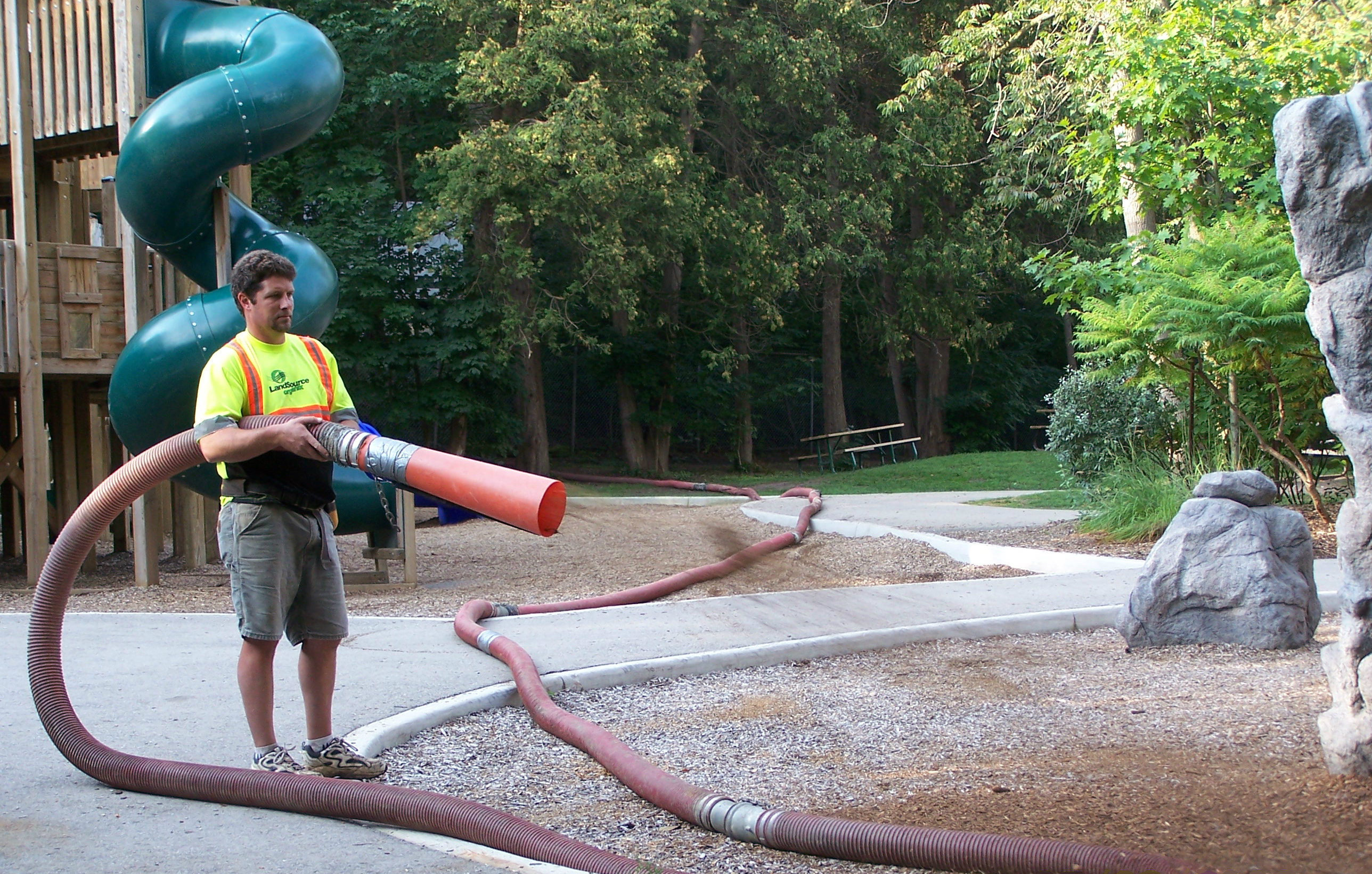Worker handles hose that blows Fibertop material at work site