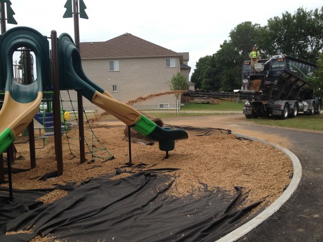 A slinger truck slings Fibertop material into residential playground work site